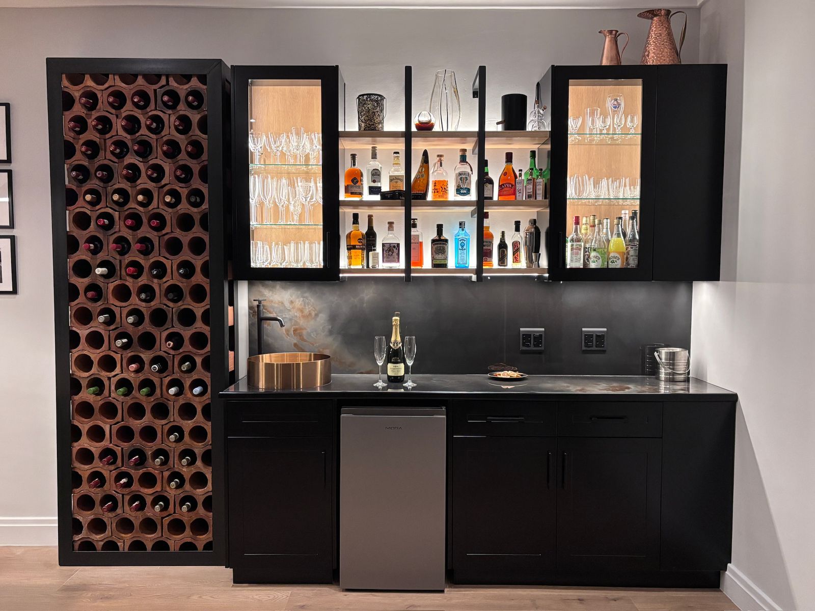 Custom black bar unit with a terracotta wine wall and lit display shelving